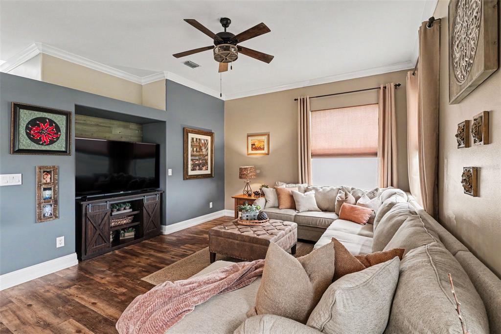 A living room features a sectional sofa, a television on a media console, and wood flooring — 663 SHERIDAN WOODS DR, MELBOURNE, FL