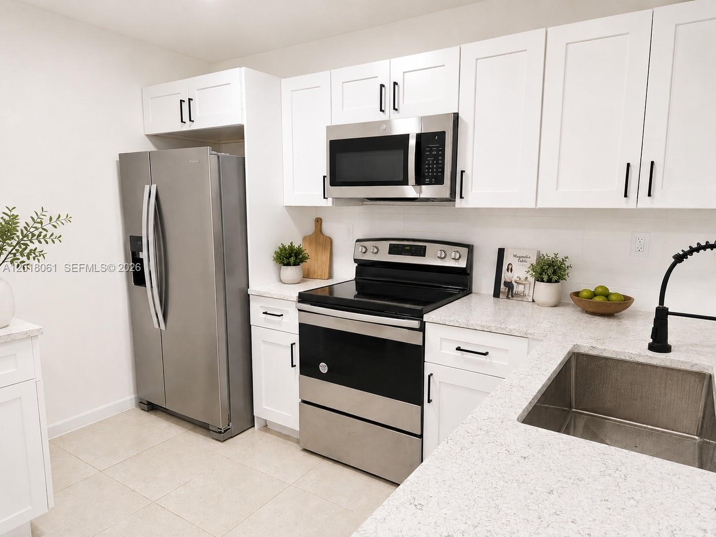 A kitchen features white cabinets, stainless steel appliances, and light-colored quartz countertops — 15721 SW 137th Ave # 202, Miami FL 33177, MIAMI, FL