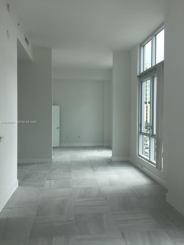An empty room features light gray tile flooring, white walls, and floor-to-ceiling windows — 9066 SW 73rd Ct # 503, Miami FL 33156, MIAMI, FL