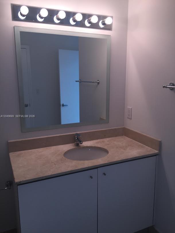 A bathroom features a vanity with a stone countertop, a mirror, and a light fixture — 9066 SW 73rd Ct # 503, Miami FL 33156, MIAMI, FL