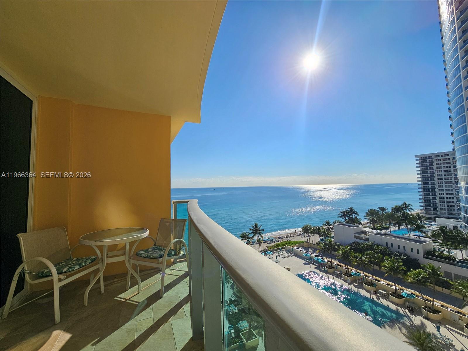 A balcony with a small table and two chairs overlooks the ocean and pool area — 2501 S Ocean Dr, Hollywood FL 33019, HOLLYWOOD, FL