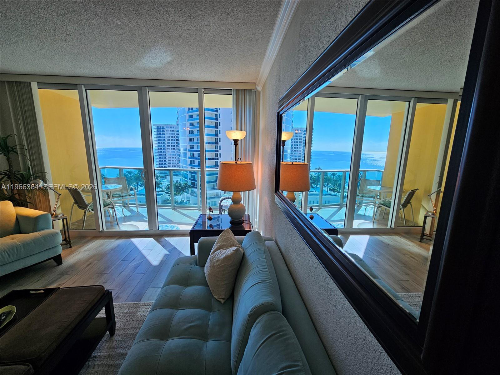 A living room features a light blue sofa, a large wall mirror, and balcony ocean views — 2501 S Ocean Dr, Hollywood FL 33019, HOLLYWOOD, FL
