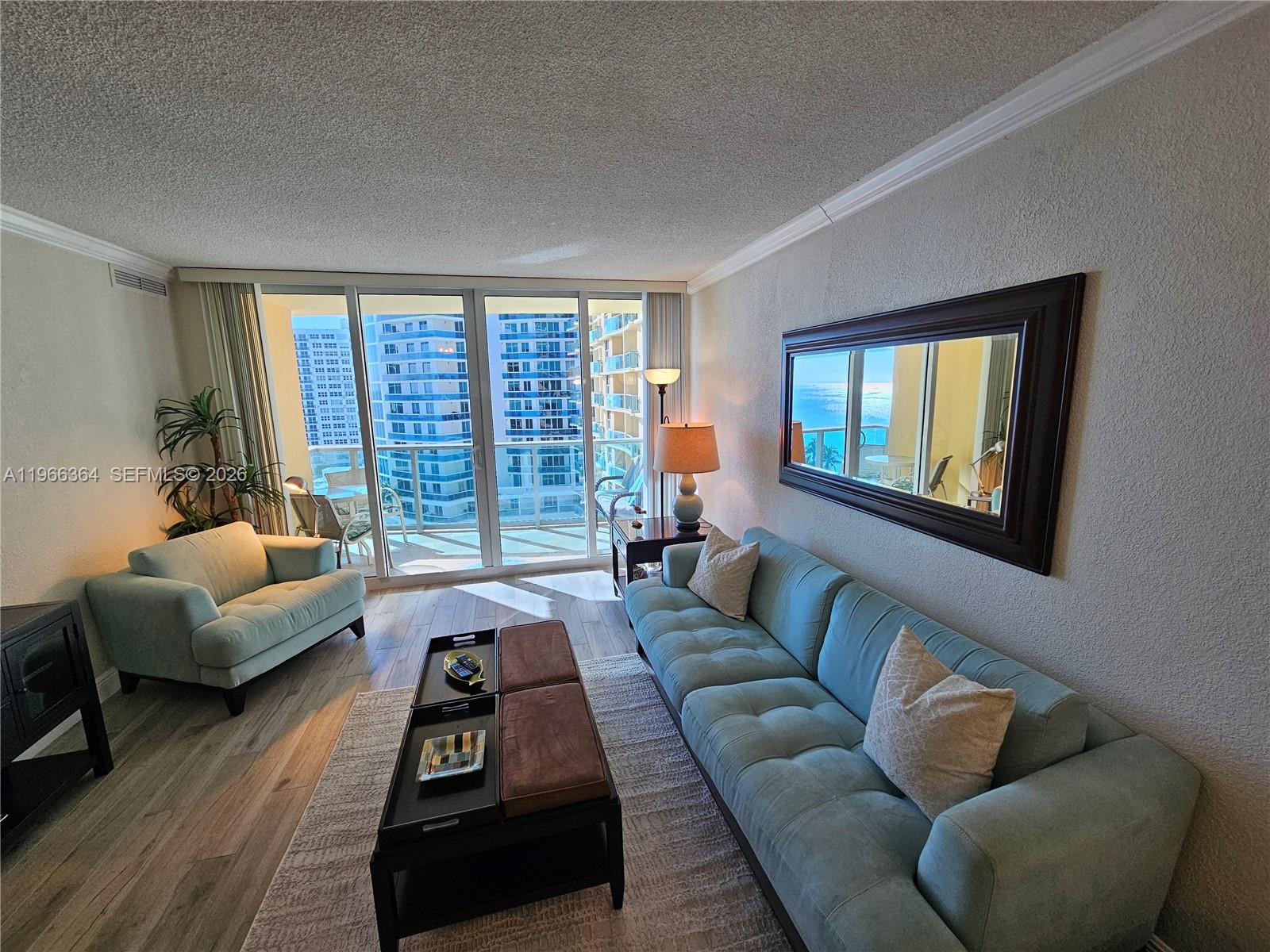 A living room features a blue sofa, matching armchair, coffee table, and balcony ocean views — 2501 S Ocean Dr, Hollywood FL 33019, HOLLYWOOD, FL