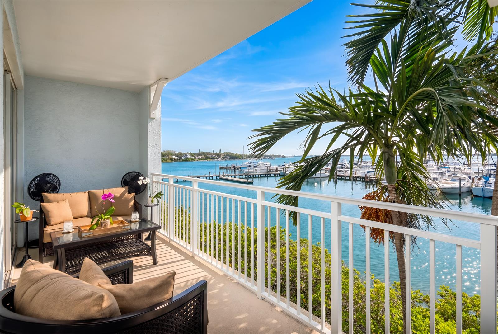 A balcony with outdoor seating overlooks a marina with boats on a sunny day — 875 NW Flagler Avenue # 203, Stuart FL 34994, STUART, FL