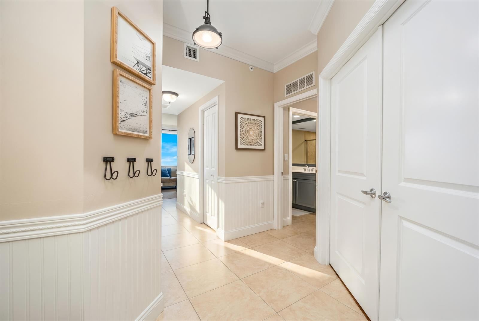 A hallway with beige walls, white wainscoting, tile flooring, and several closed white doors — 875 NW Flagler Avenue # 203, Stuart FL 34994, STUART, FL