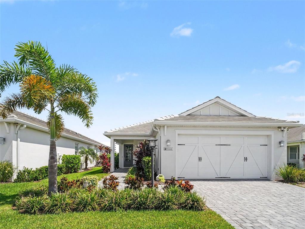A single-story house with a white garage, a paved driveway, and a palm tree — 8144 STERNWAY ROAD, SARASOTA, FL