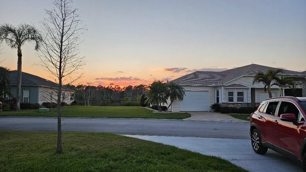 A red SUV is parked in front of a suburban house at sunset — 1098 MOTORCOACH DRIVE, POLK CITY, FL