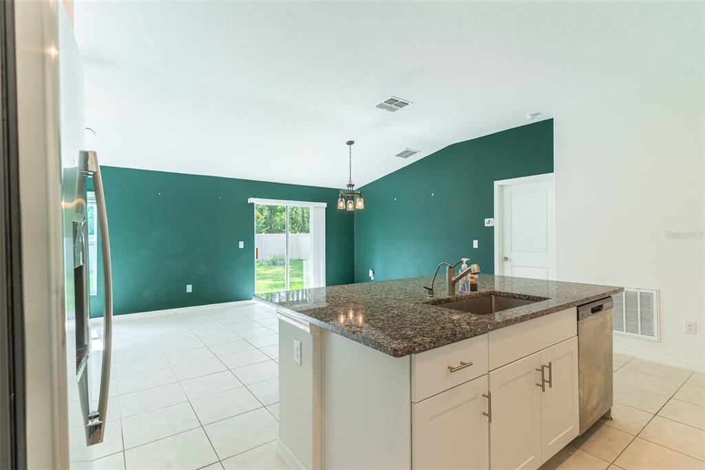 A kitchen island with granite countertops sits in front of a room with green walls — 1863 YELLOW TRAIL, LAKELAND, FL