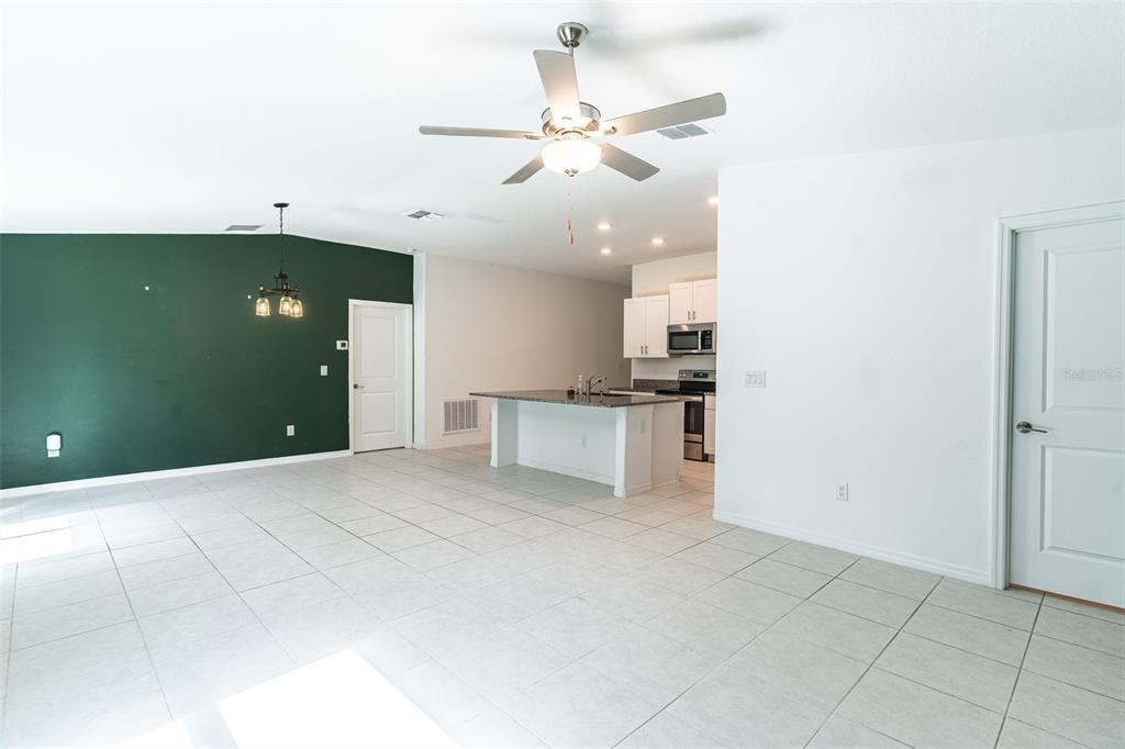 An open-concept living area features a dark green accent wall, tiled floors, and a kitchen — 1863 YELLOW TRAIL, LAKELAND, FL