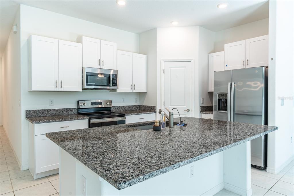 A kitchen features white cabinets, granite countertops, a large island, and stainless steel appliances — 1863 YELLOW TRAIL, LAKELAND, FL