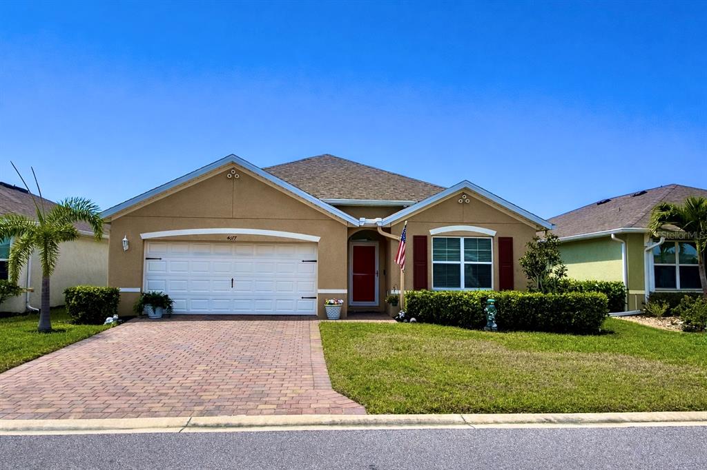 A single-story house with a tan stucco exterior, a paved driveway, and a red front door — 4077 MANATEE LANE, PUNTA GORDA, FL