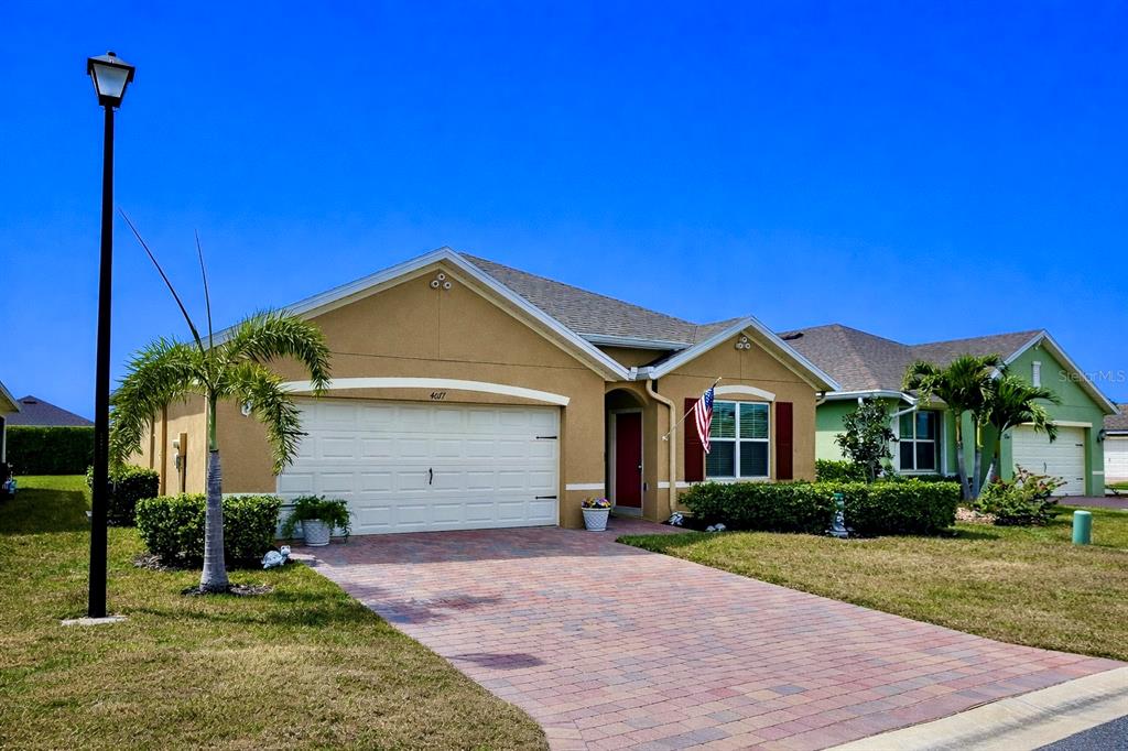 A single-story suburban house with a tan stucco exterior, a paved driveway, and a palm tree — 4077 MANATEE LANE, PUNTA GORDA, FL