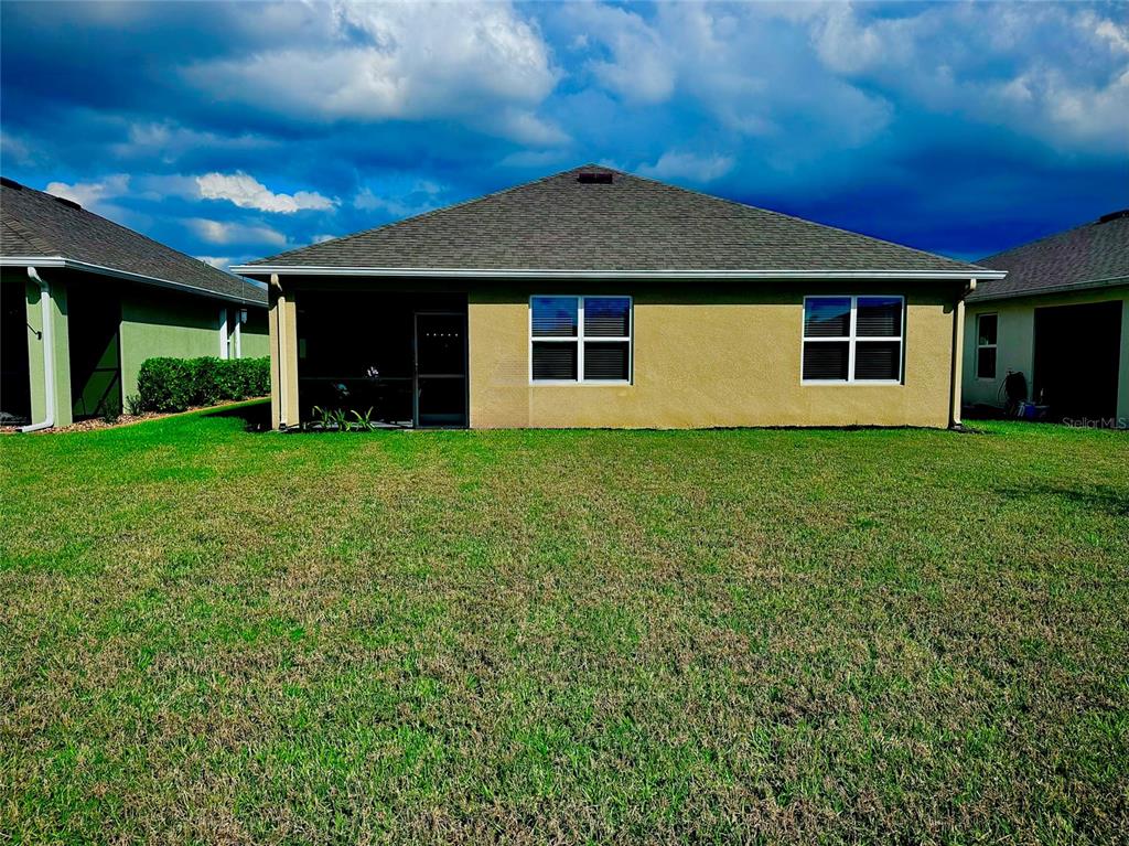 The rear exterior of a single-story house features a screened-in patio and a grassy yard — 4077 MANATEE LANE, PUNTA GORDA, FL