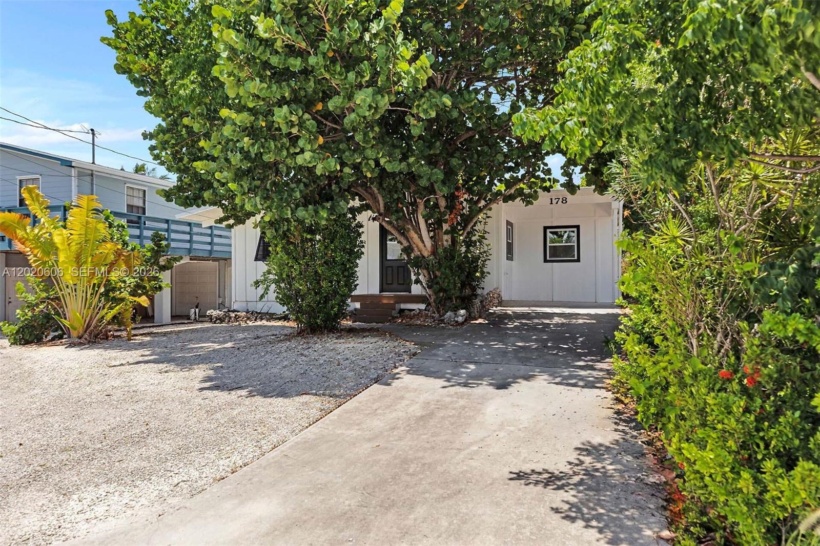 A single-story house with a concrete driveway, a large tree, and gravel landscaping — 178 Coral Ave, Tavernier FL 33070, TAVERNIER, FL