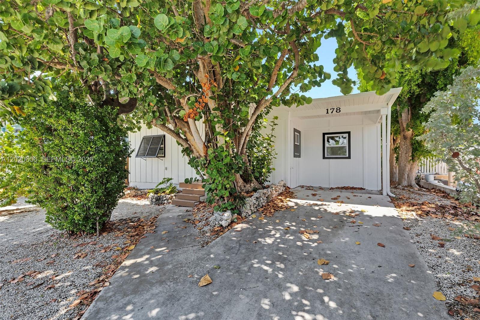 A white house with a concrete driveway and a large tree in the front yard — 178 Coral Ave, Tavernier FL 33070, TAVERNIER, FL