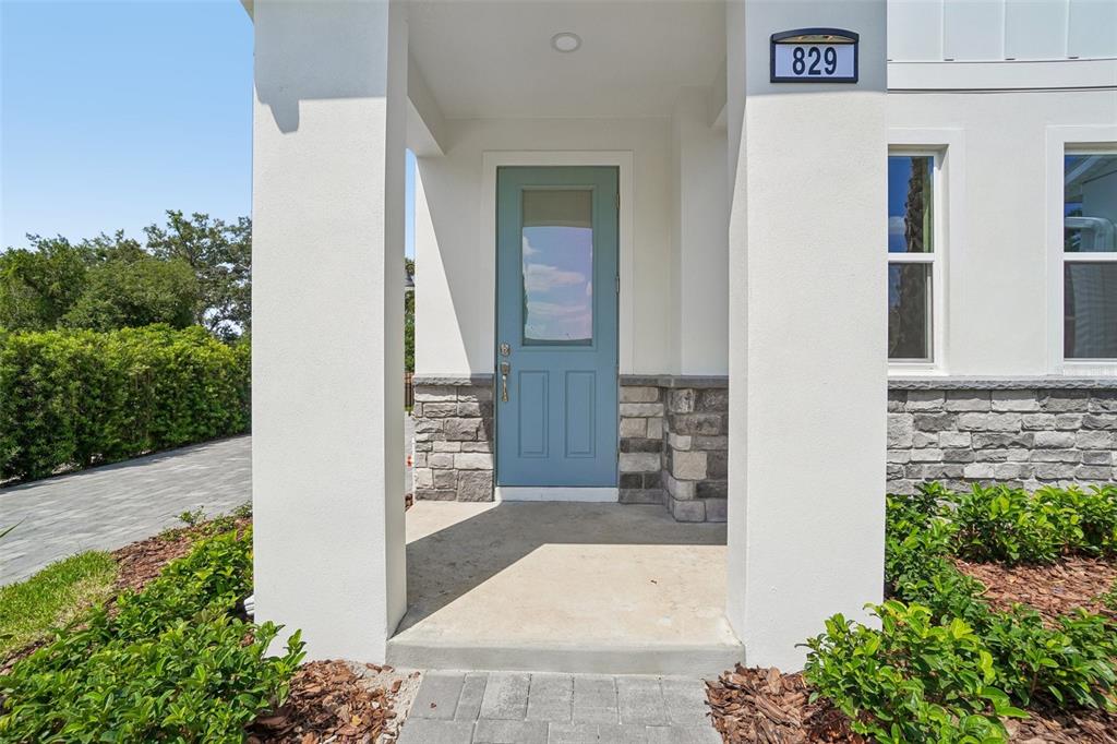 A light blue front door is set within a covered porch featuring stone veneer accents — 616 SILVER STREAM COURT, BRANDON, FL