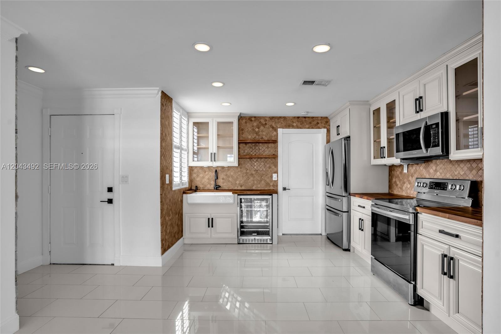 A kitchen features white cabinets, wood countertops, stainless steel appliances, and a tiled backsplash — 1231 Sorrento Dr # 1231, Weston FL 33326, WESTON, FL