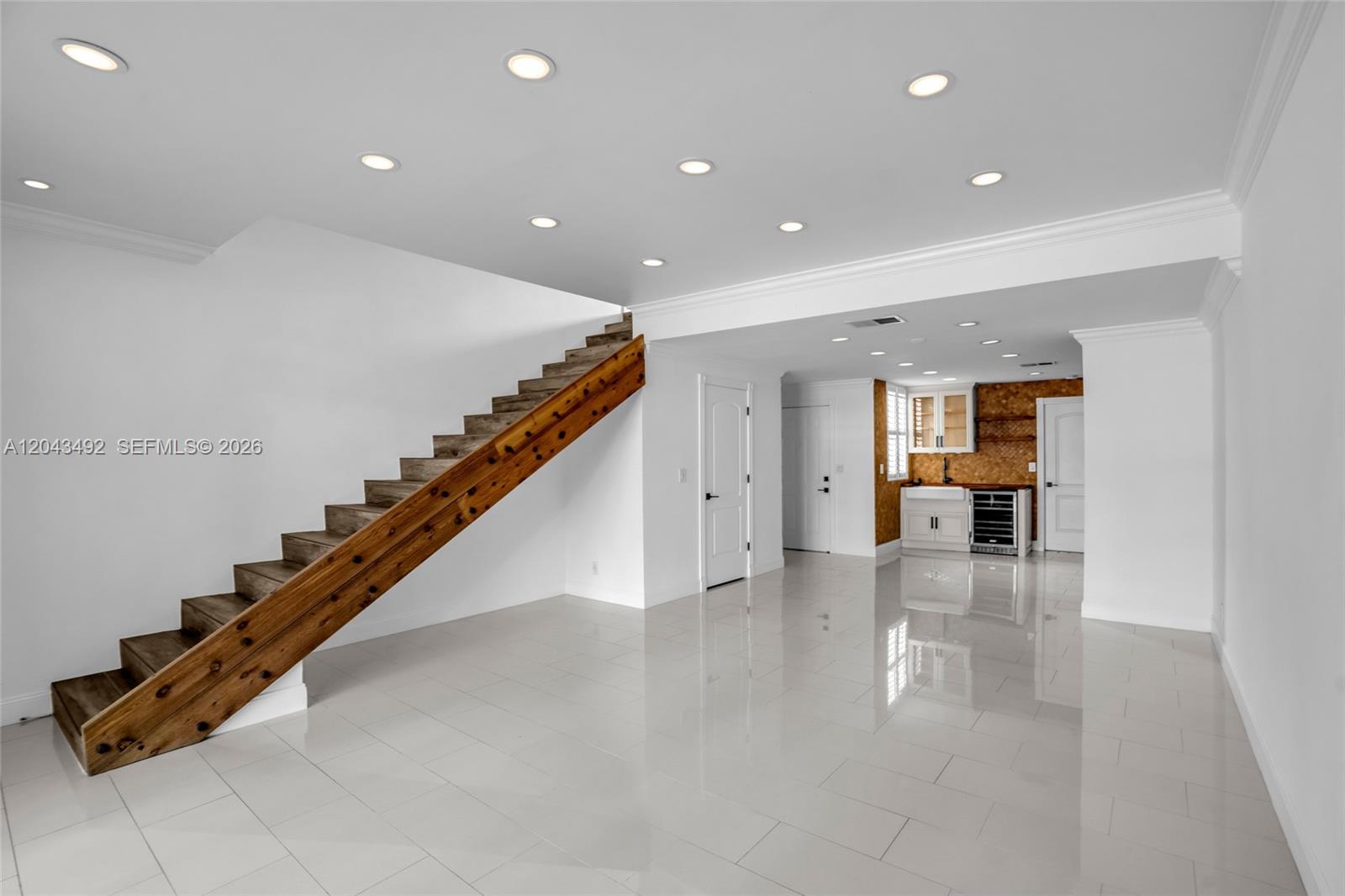 A modern room features white tile floors, a wooden staircase, and a small wet bar — 1231 Sorrento Dr # 1231, Weston FL 33326, WESTON, FL