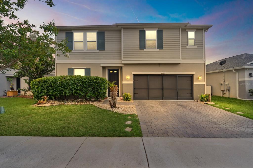 A two-story house with gray siding, a paved driveway, and a manicured front hedge — 6416 DOMENICO COURT, GROVELAND, FL