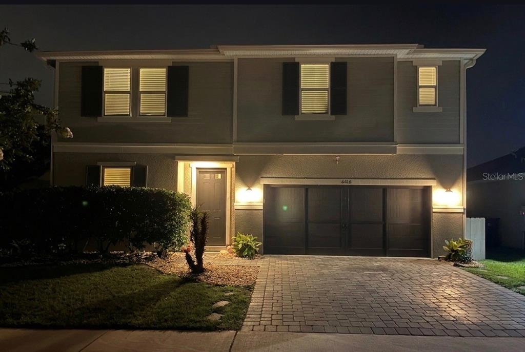 A two-story house exterior at night featuring a paved driveway, garage, and front entrance — 6416 DOMENICO COURT, GROVELAND, FL