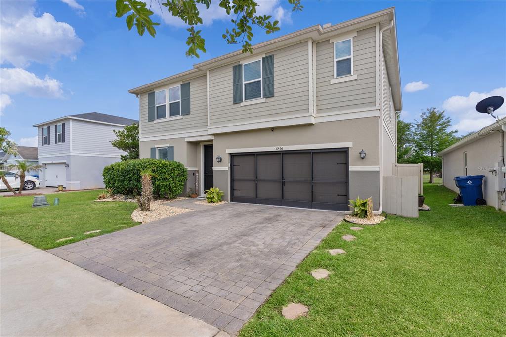 A two-story house with a paved driveway, a dark garage door, and light-colored siding — 6416 DOMENICO COURT, GROVELAND, FL