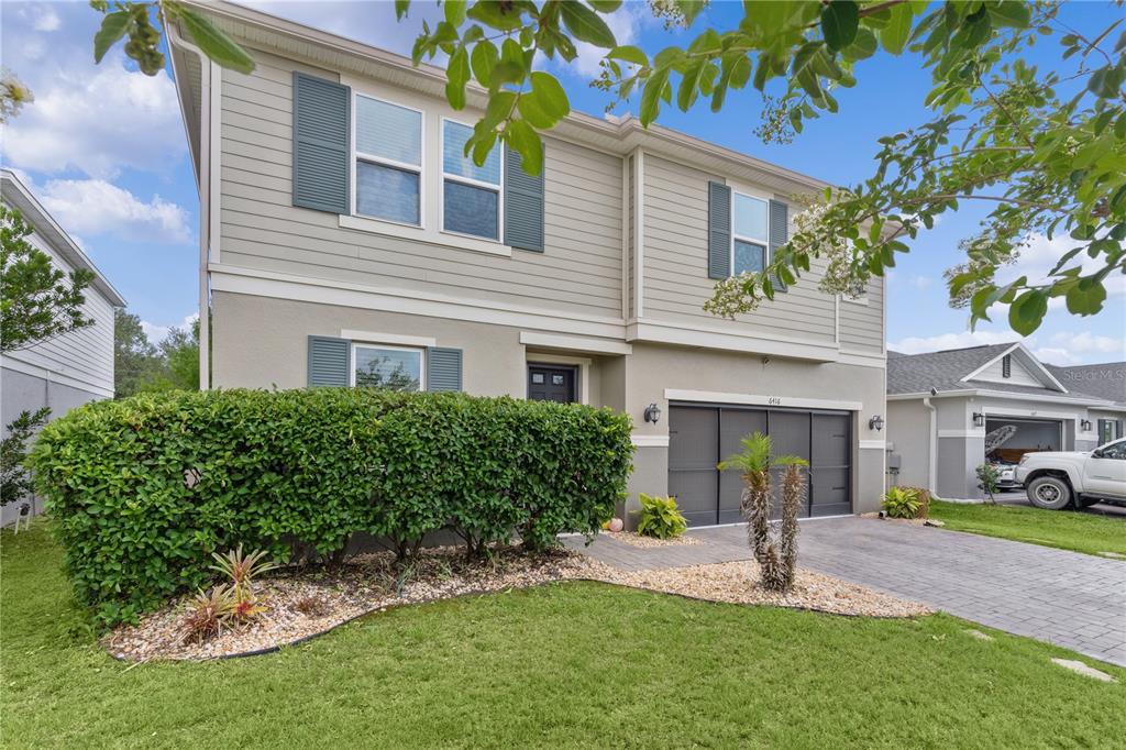 A two-story house with light siding, dark shutters, a hedge, and a paved driveway — 6416 DOMENICO COURT, GROVELAND, FL