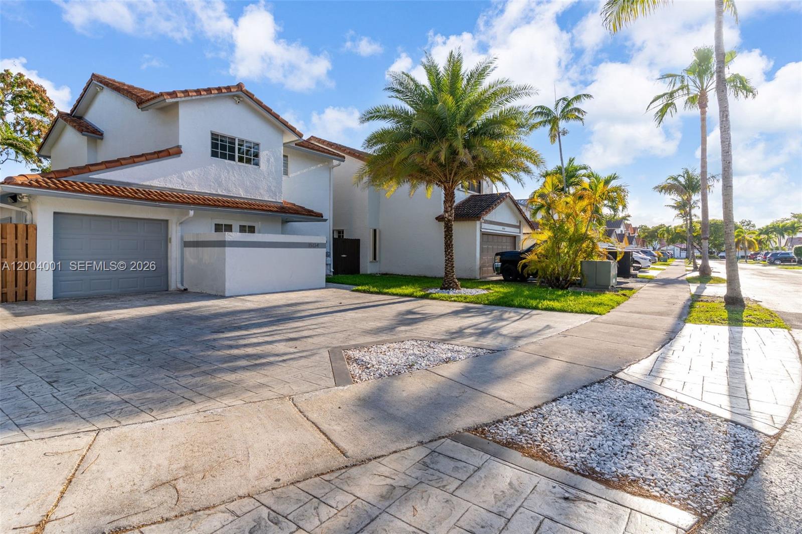 A two-story white house with a tiled roof and a paved driveway sits on a street — 15134 SW 94th Ter, Miami FL 33196, MIAMI, FL
