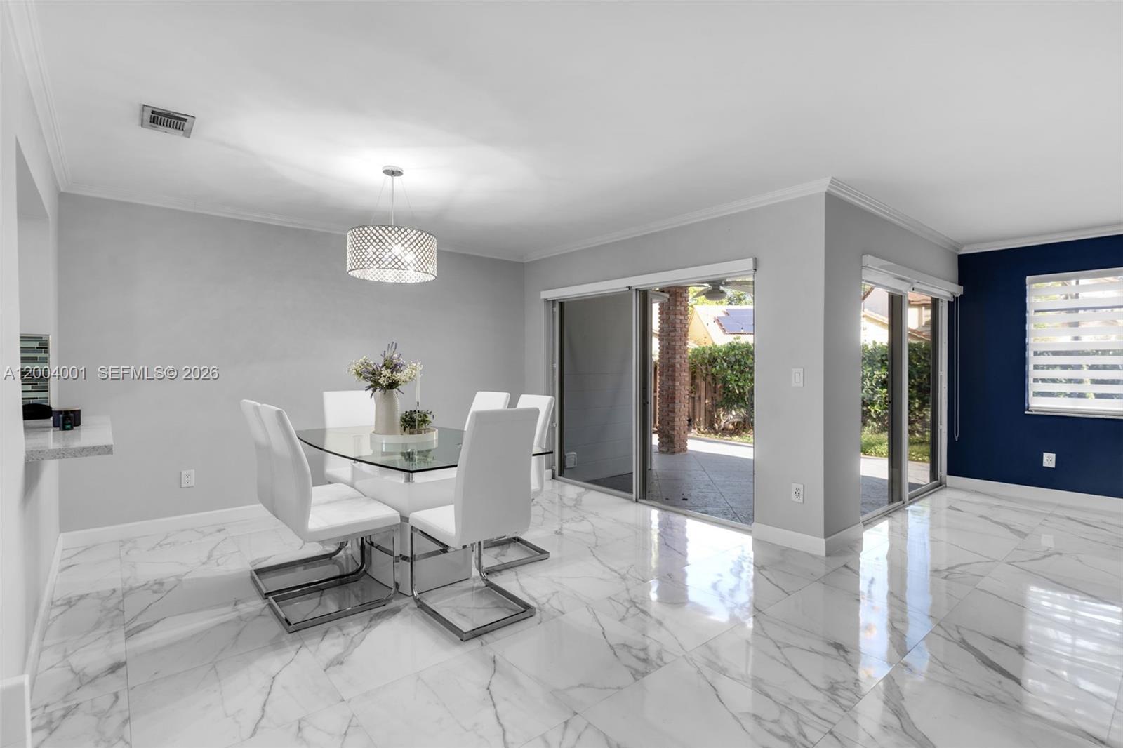 A dining room features white chairs, a glass table, marble floors, and sliding glass doors — 15134 SW 94th Ter, Miami FL 33196, MIAMI, FL