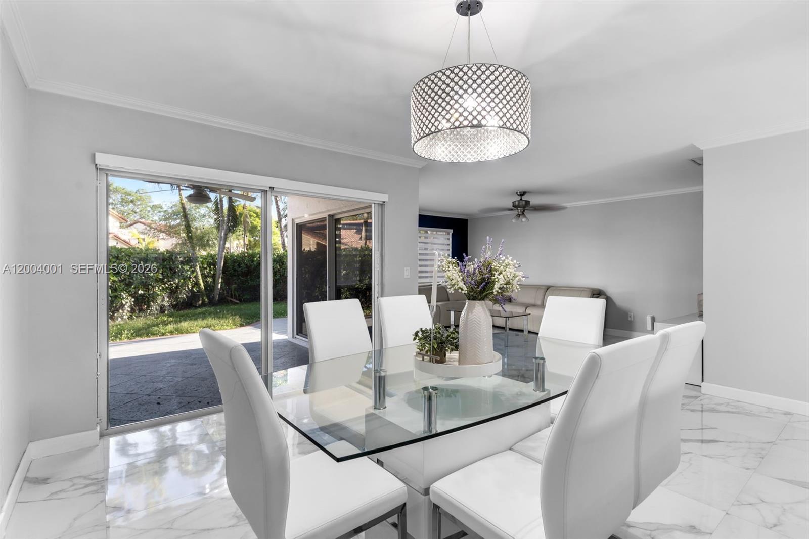 A dining room features a glass table, white chairs, a chandelier, and sliding glass doors — 15134 SW 94th Ter, Miami FL 33196, MIAMI, FL
