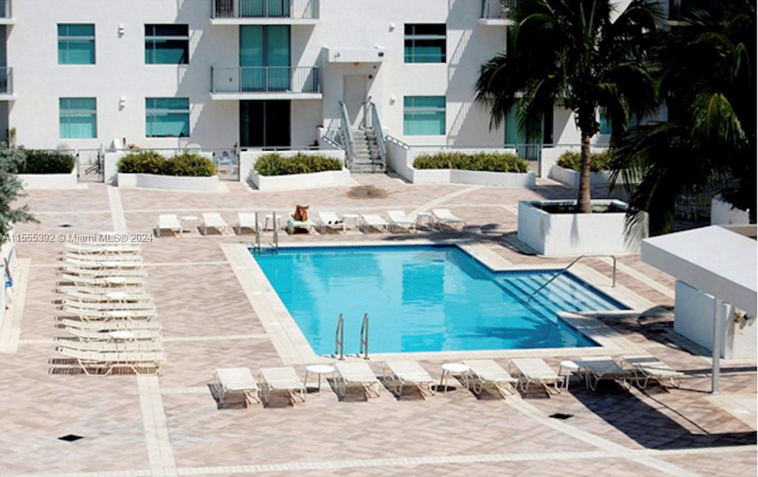 An outdoor swimming pool area with lounge chairs and a multi-story white building — 140 S Dixie Hwy # 521, Hollywood FL 33020, HOLLYWOOD, FL