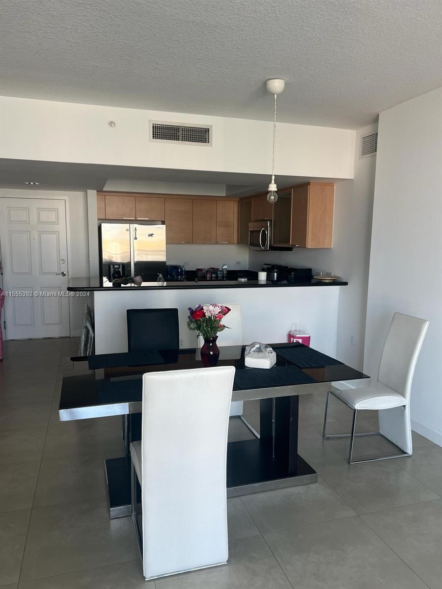 A dining area with a black table and white chairs sits before an open kitchen — 140 S Dixie Hwy # 521, Hollywood FL 33020, HOLLYWOOD, FL