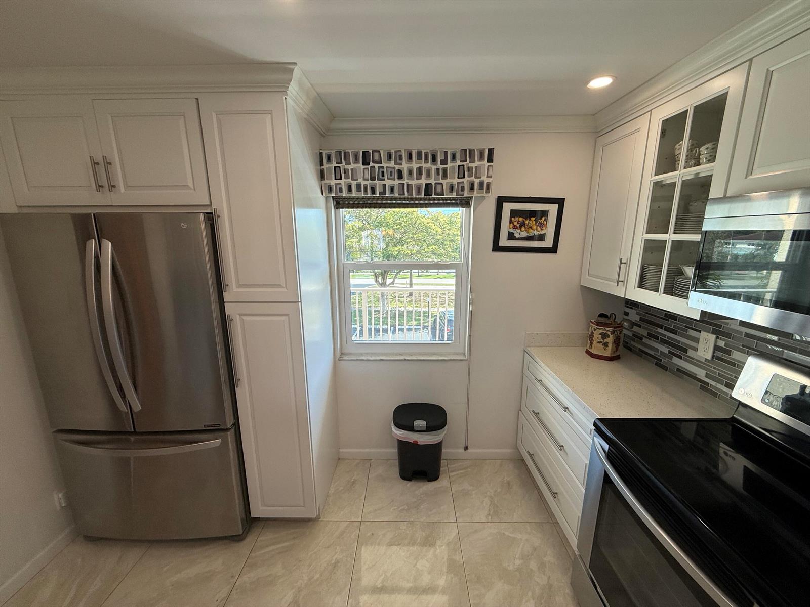 A kitchen features white cabinets, stainless steel appliances, a window, and light-colored tile flooring — 1024 SE 5th Avenue # 308, Dania Beach FL 33004, DANIA BEACH, FL