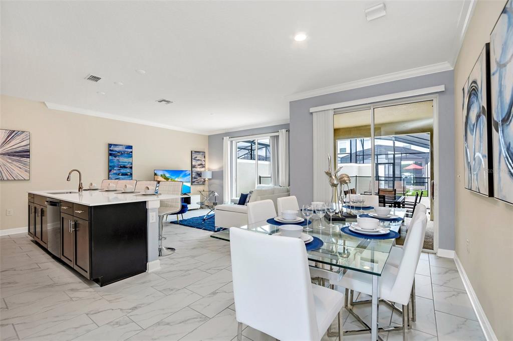 A kitchen with a dark island and a dining area with a glass table — 2861 SIMILE STREET, KISSIMMEE, FL