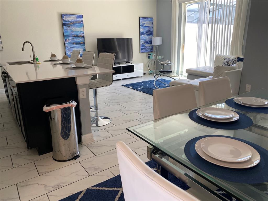 An open-concept living area features a kitchen island, dining table, and a white sofa — 2861 SIMILE STREET, KISSIMMEE, FL