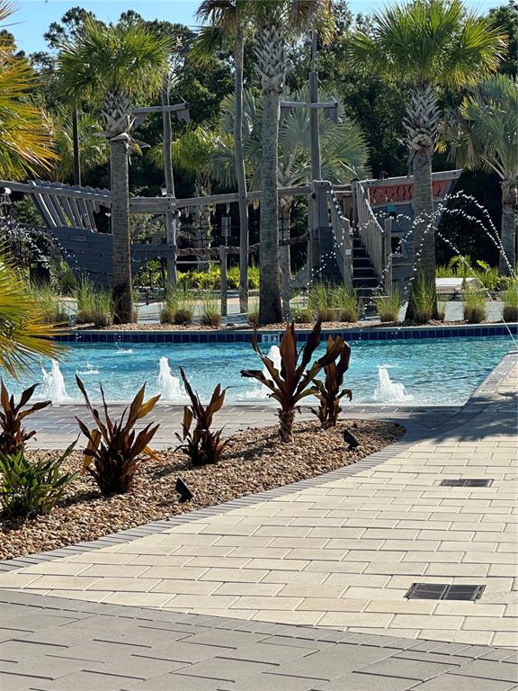 A swimming pool with fountains features a pirate ship playground in the background — 2861 SIMILE STREET, KISSIMMEE, FL