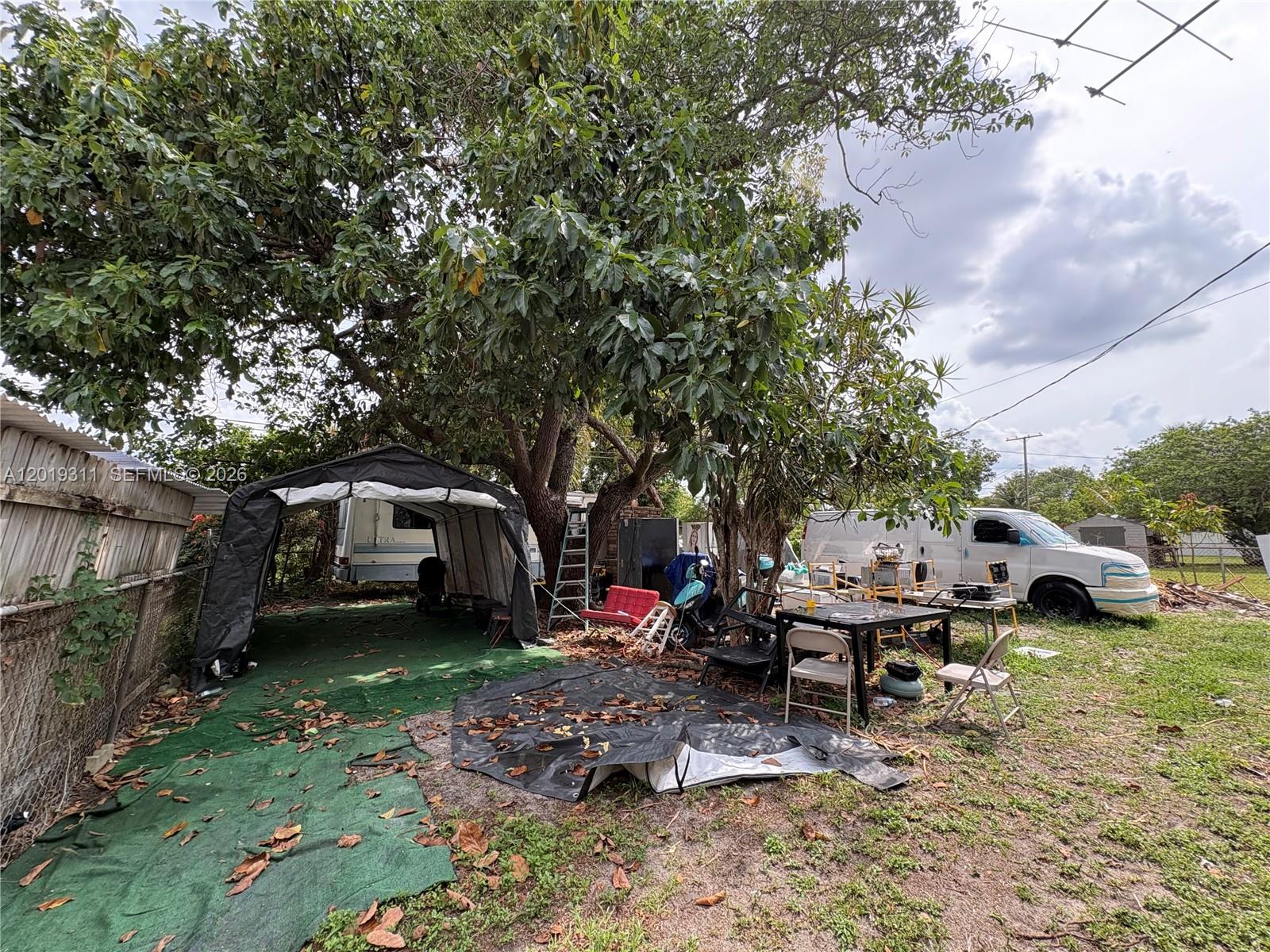 An outdoor area features a canopy, a parked van, a table, and a large tree — 1250 NW 131st St, North Miami FL 33167, NORTH MIAMI, FL