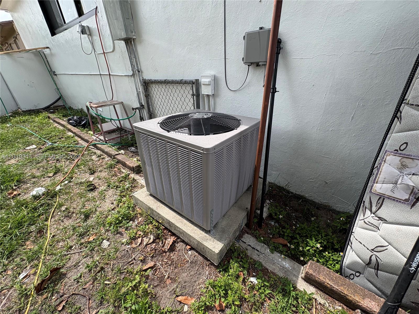 An outdoor air conditioning unit sits on a concrete pad next to a white wall — 1250 NW 131st St, North Miami FL 33167, NORTH MIAMI, FL