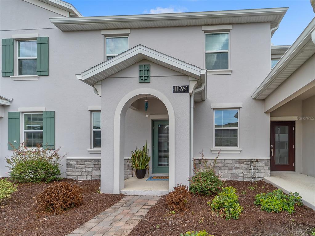 The exterior of a two-story house features a stone-accented facade, green shutters, and a covered entryway — 11961 BOLDFACE DRIVE, ORLANDO, FL