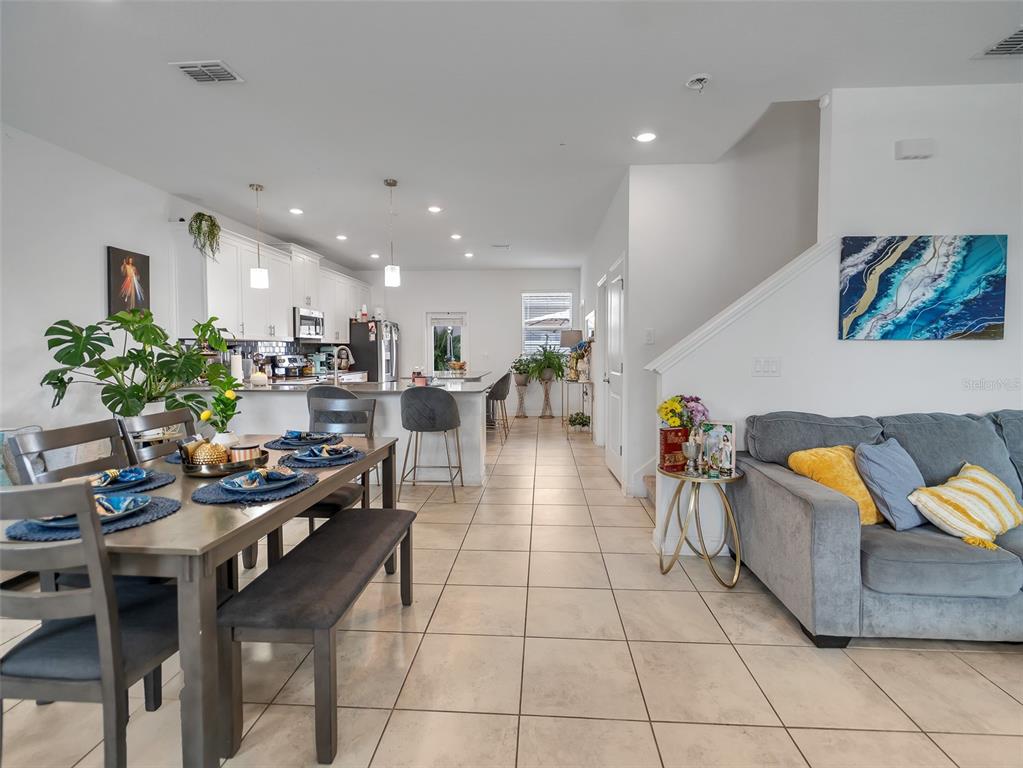 An open-concept living area features a dining set, kitchen with island, and a gray sofa — 11961 BOLDFACE DRIVE, ORLANDO, FL