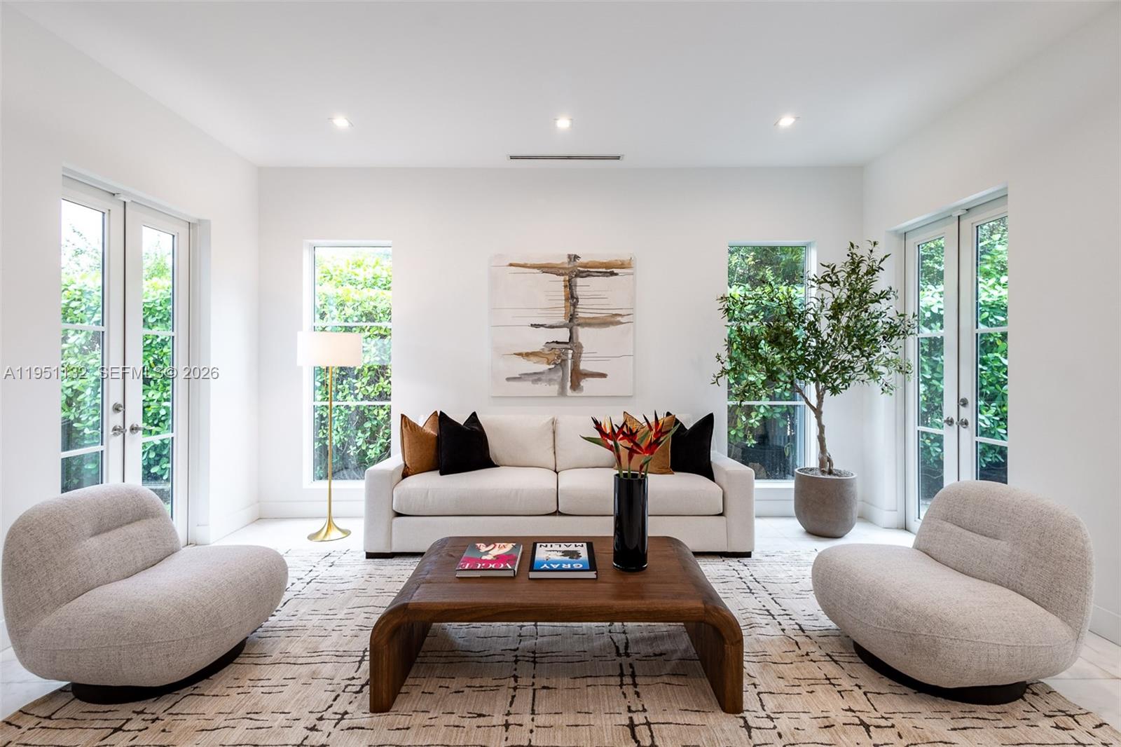 A bright living room features a white sofa, two rounded chairs, and a wooden coffee table — 315 Santander Ave # 315, Coral Gables FL 33134, CORAL GABLES, FL