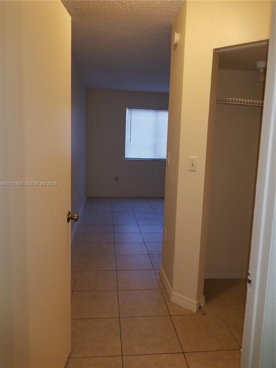 A tiled hallway leads to a bedroom with a window and an adjacent walk-in closet — 15241 SW 80th St # 201, Miami FL 33193, MIAMI, FL