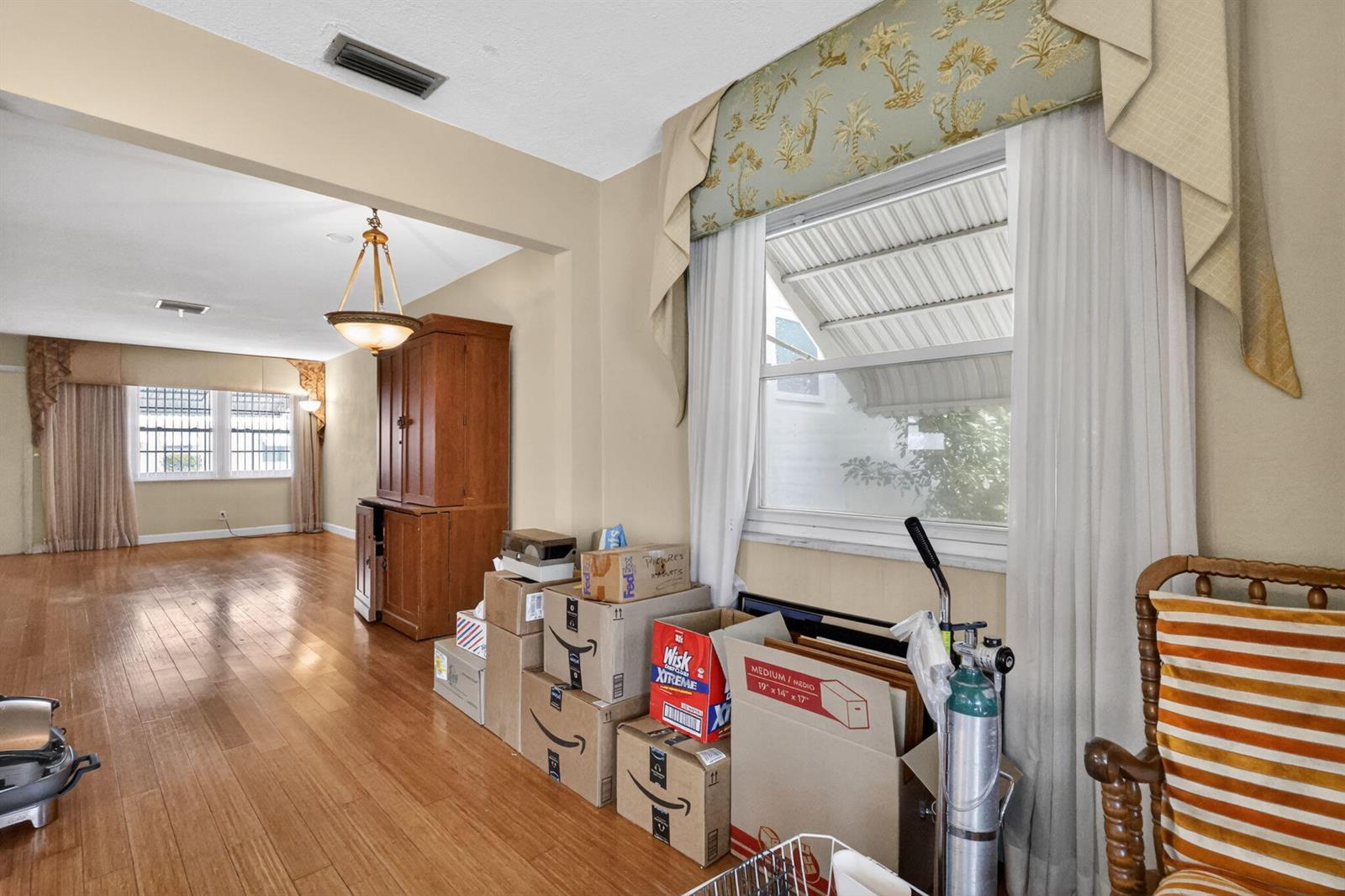 A living area with hardwood floors, a wooden cabinet, and stacked cardboard boxes by a window — 1104 W Ocean Avenue, Boynton Beach FL 33426, BOYNTON BEACH, FL
