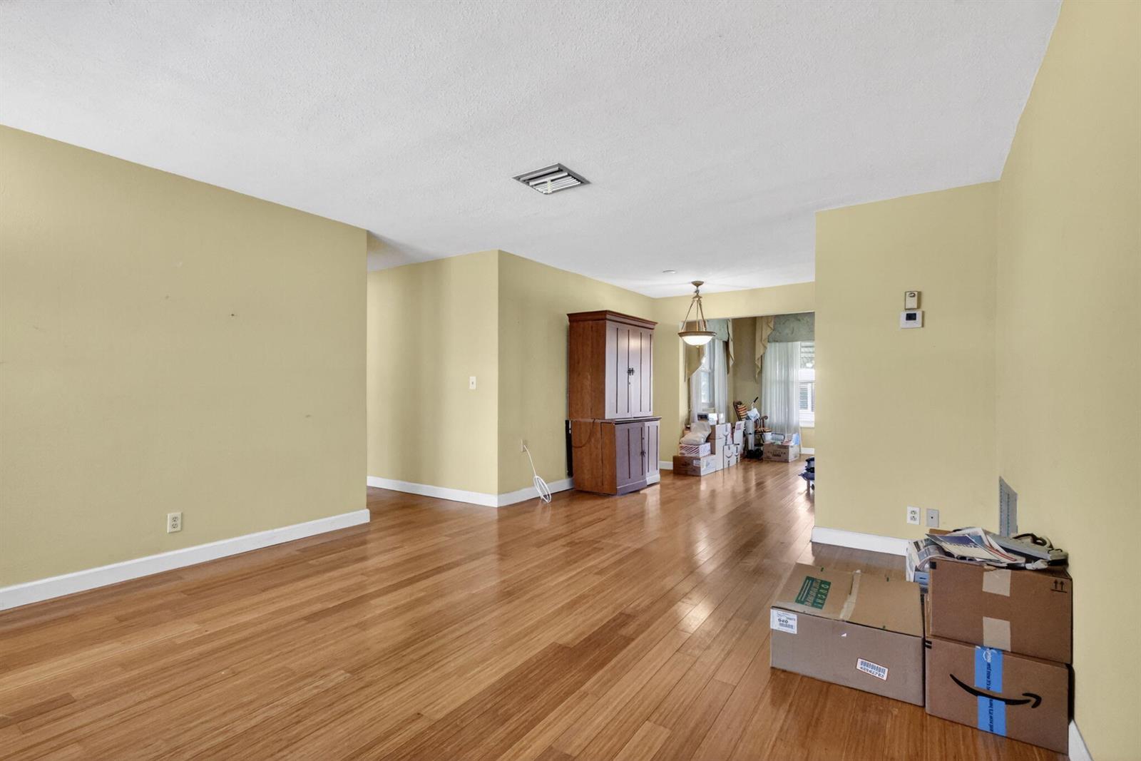 An empty living room features light yellow walls, hardwood floors, and a wooden cabinet — 1104 W Ocean Avenue, Boynton Beach FL 33426, BOYNTON BEACH, FL