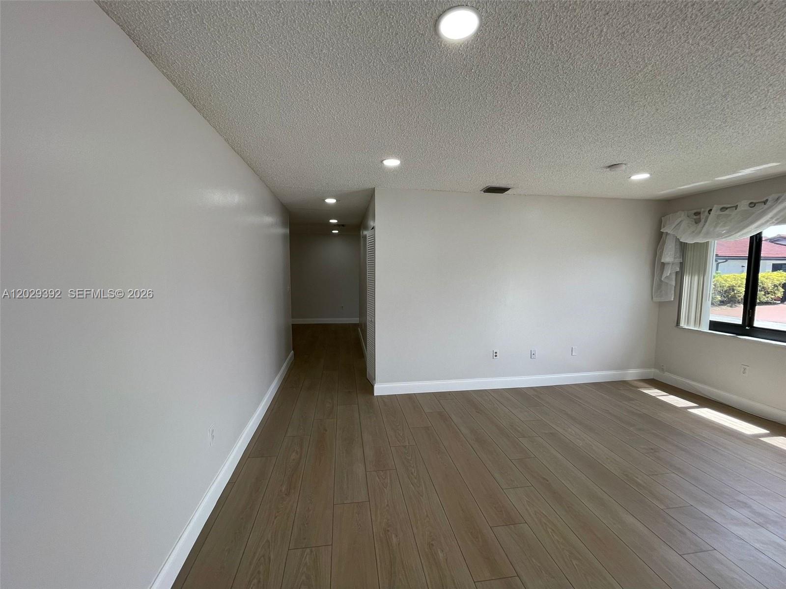 An empty room features light-colored walls, wood-look tile flooring, recessed lighting, and a window — 1727 SW 136th Pl, Miami FL 33175, MIAMI, FL