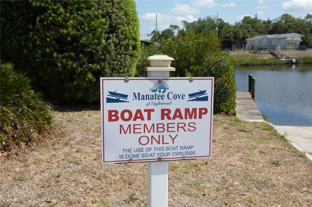 A sign for a private boat ramp stands in a grassy area near a dock — 2465 HERON DRIVE, ENGLEWOOD, FL