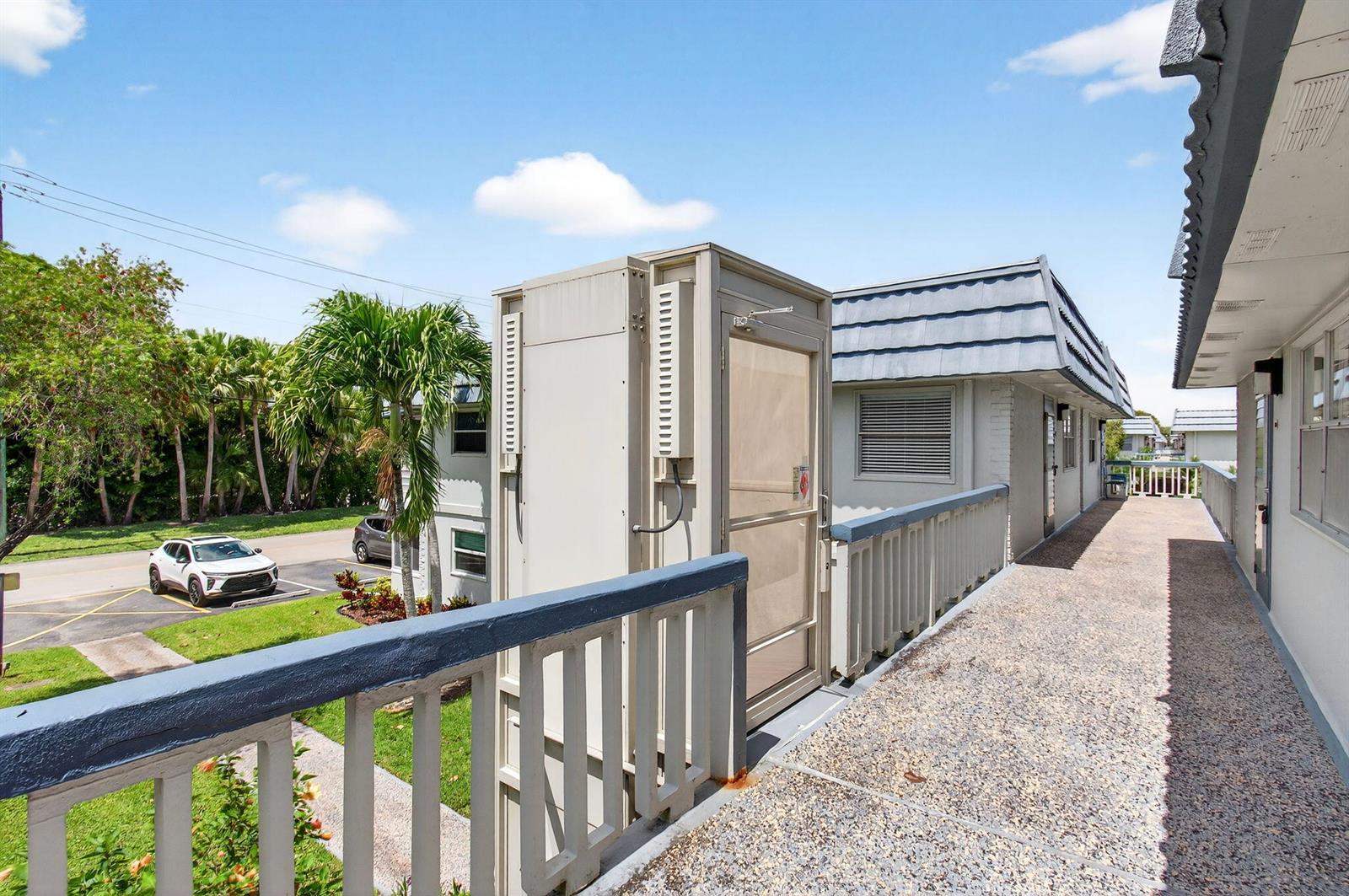 An outdoor walkway with a metal wheelchair lift leads along the side of a building — 186 Tuscany C, Delray Beach FL 33446, DELRAY BEACH, FL