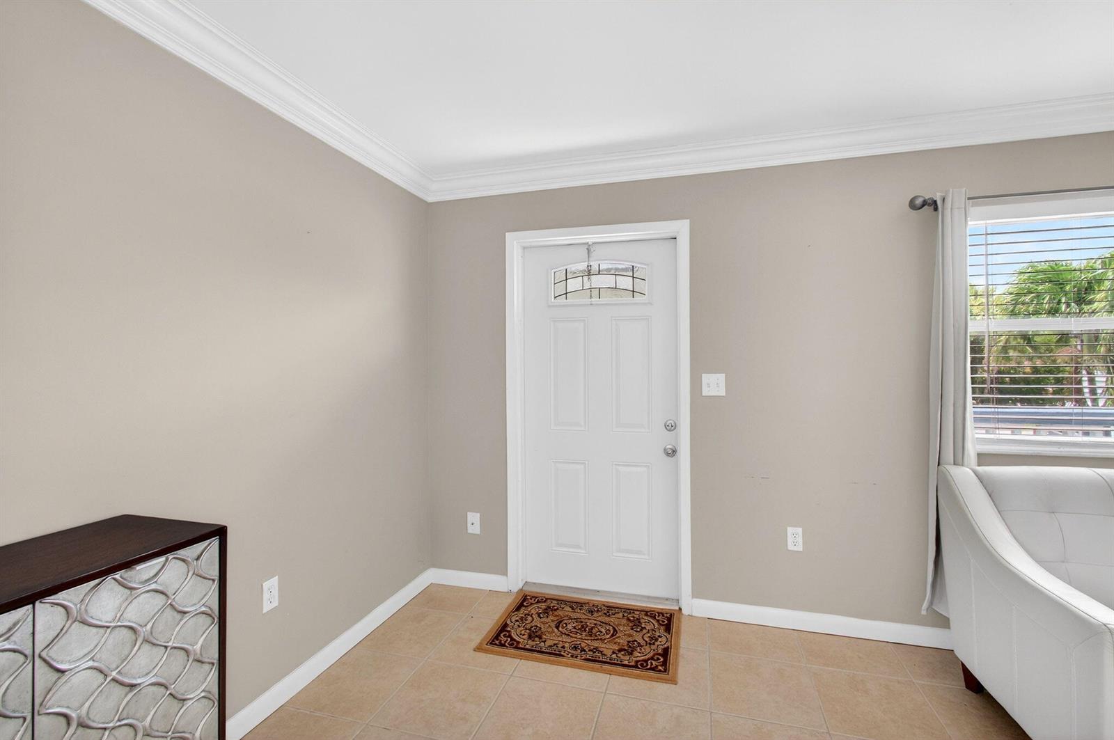 An entryway features a white front door, beige walls, and light-colored tile flooring — 186 Tuscany C, Delray Beach FL 33446, DELRAY BEACH, FL