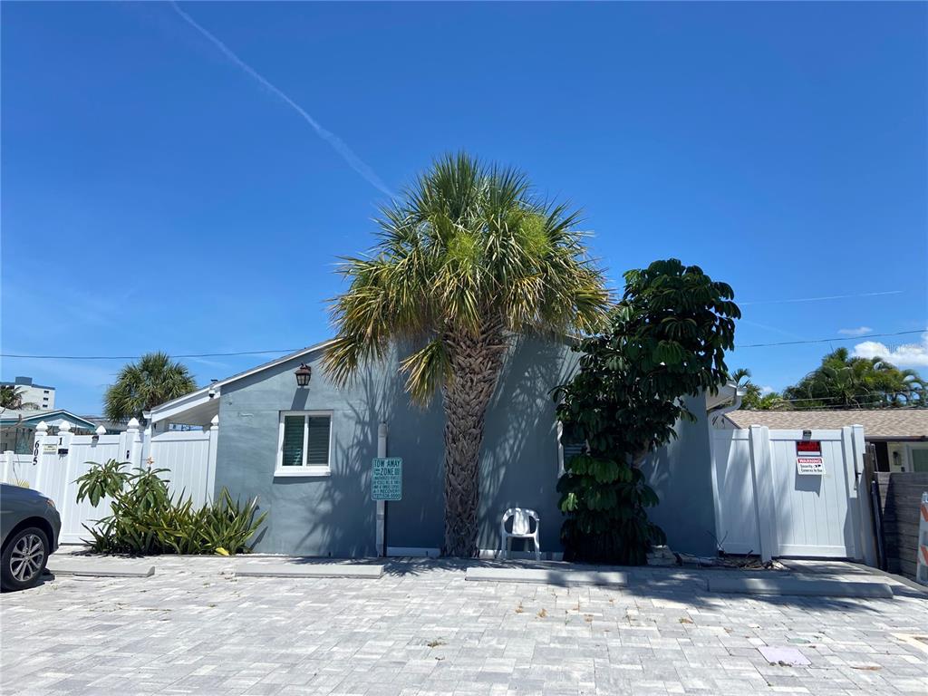 A gray exterior wall features a palm tree, a window, and a tow-away sign — 605 69TH AVENUE UNIT 1, ST PETE BEACH, FL