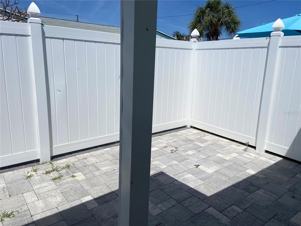 A small outdoor patio features gray stone pavers enclosed by a white vinyl privacy fence — 605 69TH AVENUE UNIT 1, ST PETE BEACH, FL