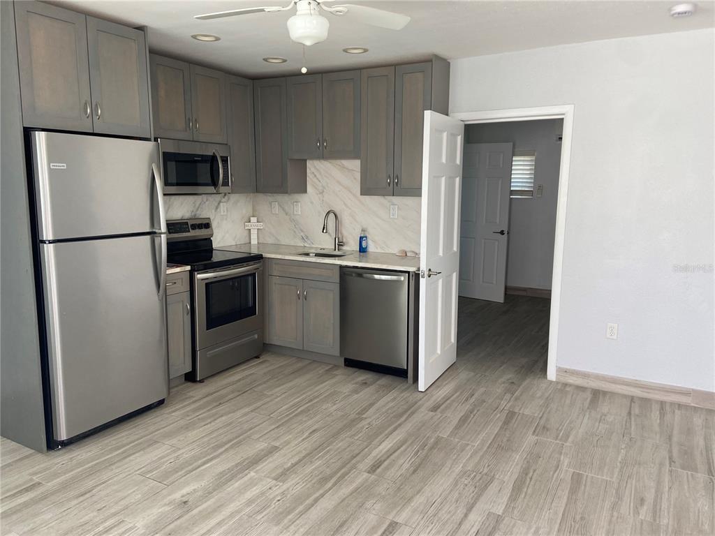 A kitchen features gray cabinets, stainless steel appliances, and wood-look flooring — 605 69TH AVENUE UNIT 1, ST PETE BEACH, FL